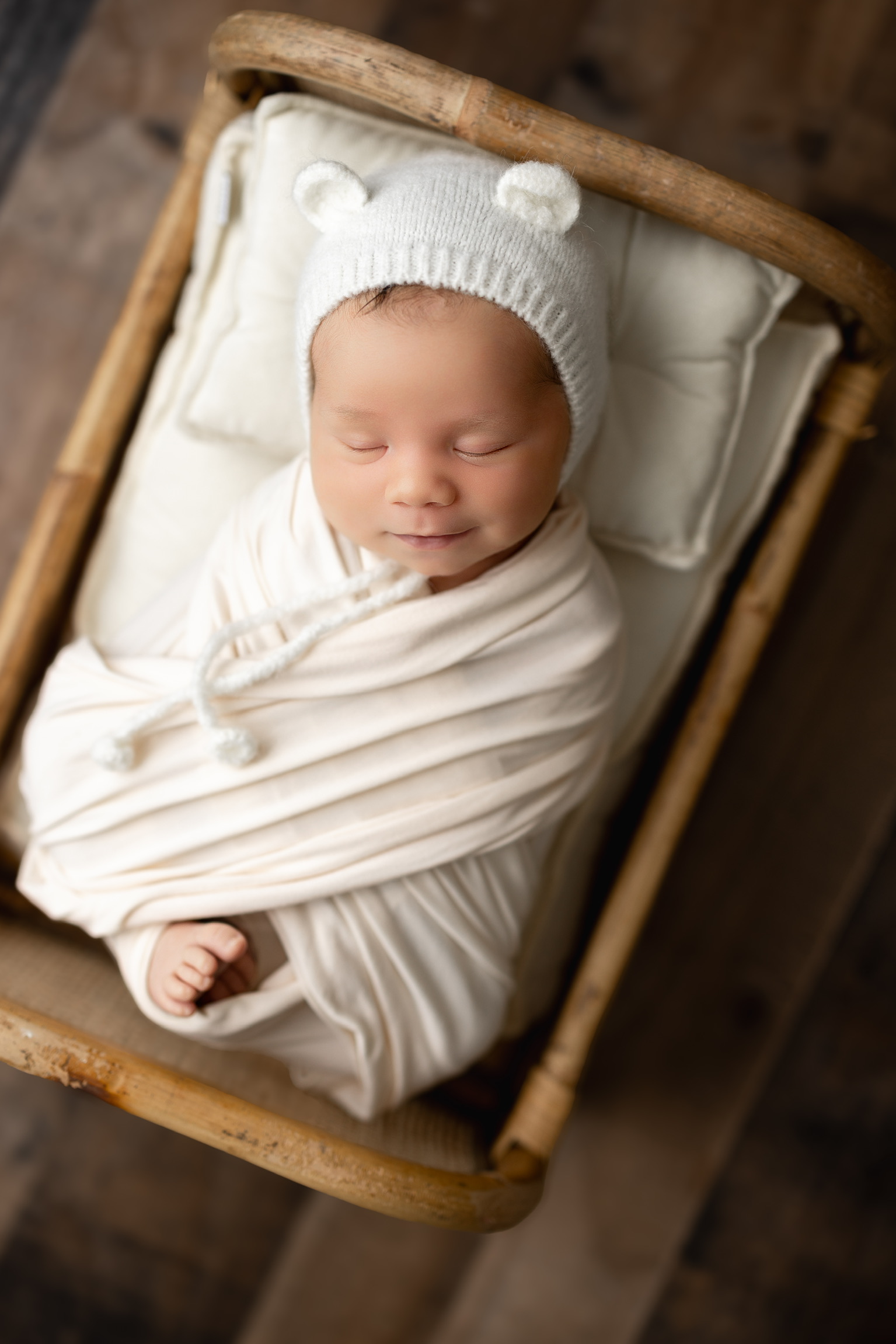 Newborn photography Tampa - baby with bear hat in cream wrap, wooden bassinet