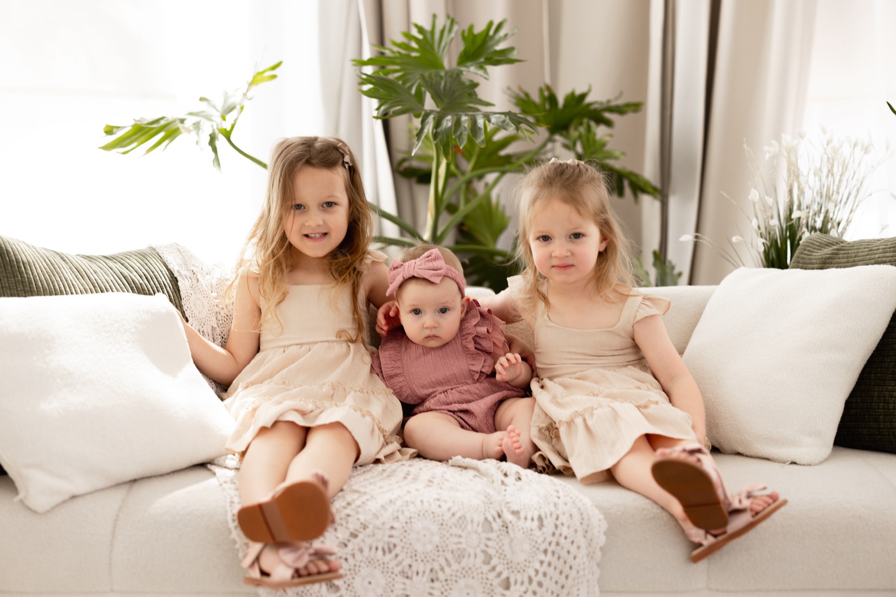 Three young sisters sitting together on a sofa
